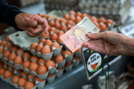 A shopper pays with a ten-euro banknote at a market in Paris